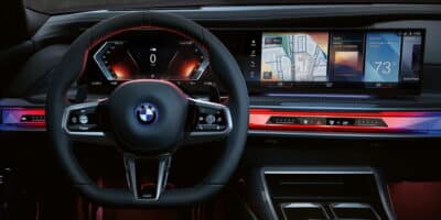 Interior view of a BMW featuring a digital dashboard and sleek steering wheel, showcasing innovations supporting BMW electric by 2030.