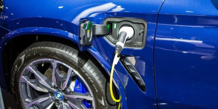 A Blue BMW X3 HPlug-in Hybrid is charging with the BMW Qmerit charger.