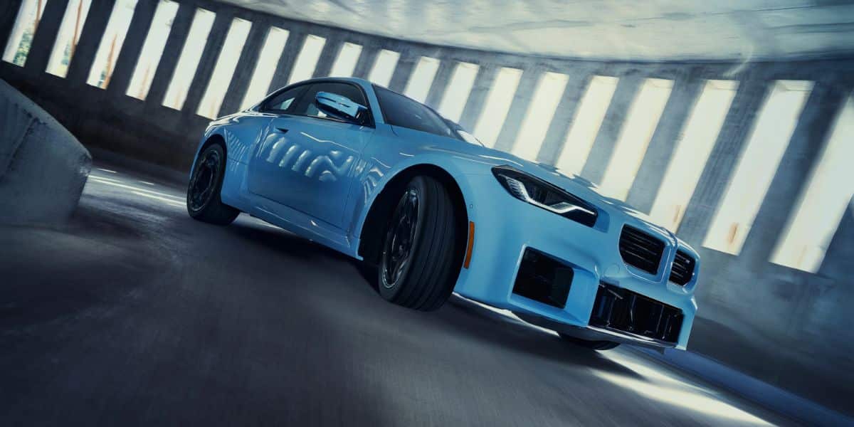 One of the blue BMW coupe models drifting in a parking garage.