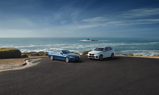 Two BMW models parked by the coast.