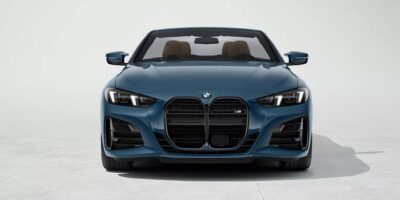 Front view of the 2025 BMW M4 Convertible in a striking blue finish, showcasing iconic kidney grilles, sleek LED headlights, and a luxurious convertible design.