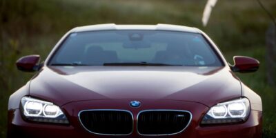 Front view of a red BMW M6 with headlights on, showcasing the bold design and grand touring character of the BMW M6.
