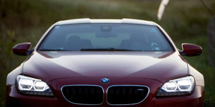 Front view of a red BMW M6 with headlights on, showcasing the bold design and grand touring character of the BMW M6.