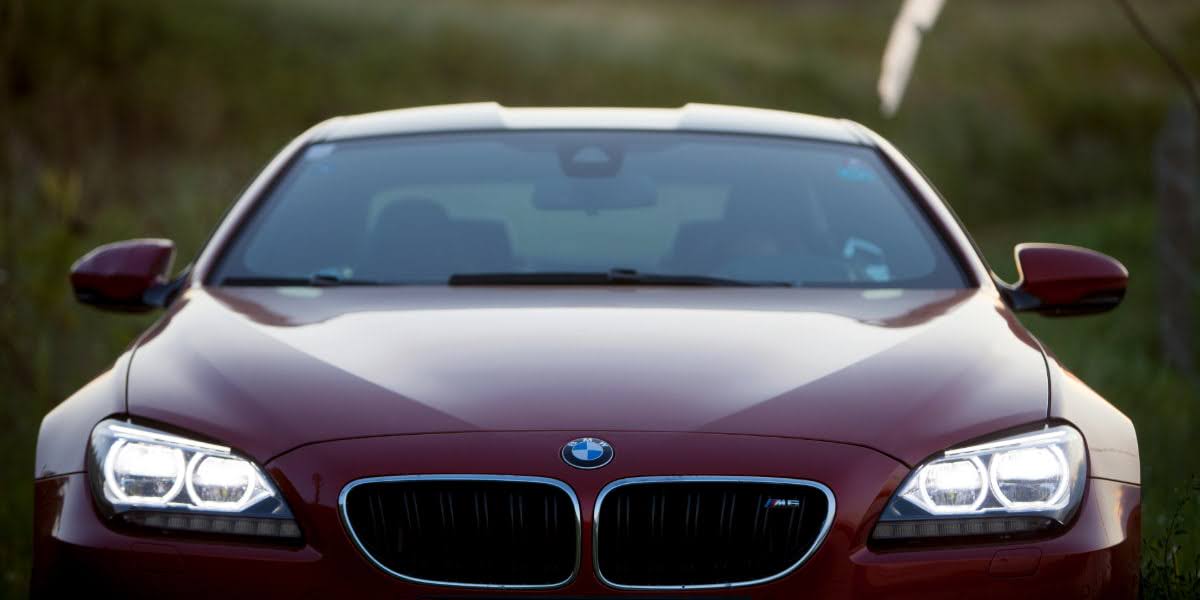 Front view of a red BMW M6 with headlights on, showcasing the bold design and grand touring character of the BMW M6.