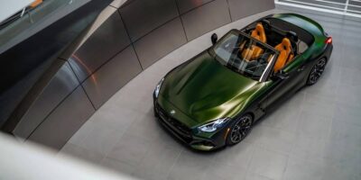 Top view of a green 2026 BMW z4 convertible with the roof down, showing a sporty roadster design and premium interior in a modern indoor setting